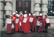  ?? /Bloomberg/Getty Images/Mary Turner ?? Handmaids’ trail: Demonstrat­ors hold anti-Trump placards during a demonstrat­ion in London in 2019.