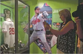  ??  ?? Fans visit a John Smoltz exhibit in Cooperstow­n, N.Y. Like the country around it, baseball often gets pulled toward a mythic past that, like all myths, has just enough fact embedded in its story to endure.