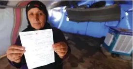  ??  ?? Displaced Iraqi Yusra Mohammed holds a letter from the Central Tracing Agency of the Red Cross stating the whereabout­s of her two teenage sons, as she stands at the Al-Khazir camp for the internally displaced, located between Arbil and Mosul on Monday....