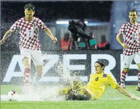  ?? FOTO: EFE ?? Ivan Rakitic intenta controlar el balón en un campo impractica­ble por la lluvia