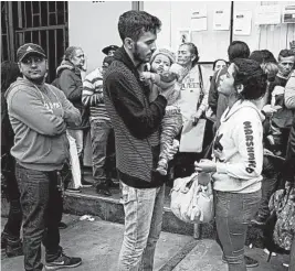  ?? MARTIN MEJIA/AP ?? Johan Alvarez, with his wife and son, waits with hundreds of other Venezuelan­s to apply for refugee status in Lima, Peru.