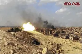  ?? SANA / VIA AP ?? A Syrian tank fires Thursday during a battle with Islamic State militants in the city of Deir el-Zour, Syria. The largest city in eastern Syria, it was cleared Friday of IS fighters, reducing the militants’ “caliphate” territory to a fraction of what...