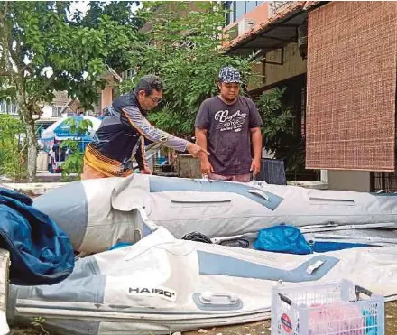  ?? NSTP PIC BY OMAR AHMAD ?? Mohd Afiq Yuzaini (right) and his father, Yuzaini Mohd Yusop, examining Afiq’s inflatable boat at his home in Villa Ros, Taman Tampoi Indoh, Johor Baru, yesterday.