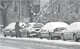  ??  ?? A woman wipes the snow off her car in Chicago on Tuesday.