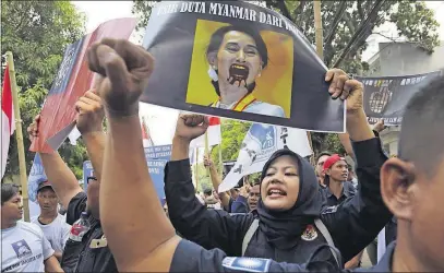  ?? [TATAN SYUFLANA/THE ASSOCIATED PRESS] ?? A Muslim woman shouts slogans as she holds up a poster bearing a defaced portrait of Myanmar State Counsellor Aung San Suu Kyi during a rally against the persecutio­n of Rohingya Muslims outside the Myanmar Embassy in Jakarta, Indonesia. Hundreds of...