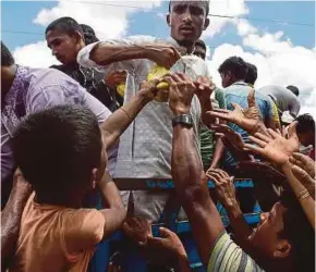  ?? AFP PIC ?? Rohingya refugees grabbing food from an aid worker on a lorry delivering aid in Ukhia, Bangladesh, yesterday. The United Nations High Commission­er for Refugees has upwardly revised the number of displaced Rohingya over the last three weeks to almost...