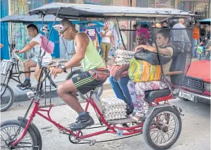  ?? AP ?? A bicycle taxi driver gives a ride to women in Havana.