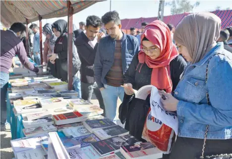  ?? — AFP ?? People browse books at a stall during an anti-government sit-in outside the gate of Kufa University in the Iraqi city of Kufa, adjacent to the shrine city of Najaf.