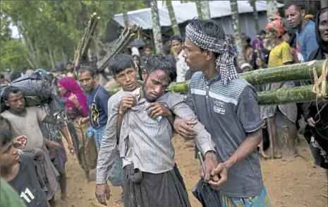  ?? Bernat Armangue/Associated Press ?? Kifawet Ullah is helped by other newly arrived Rohingya after he collapsed while waiting to have his token validated to collect a bag of rice distribute­d by aid agencies Saturday in Kutupalong, Bangladesh.