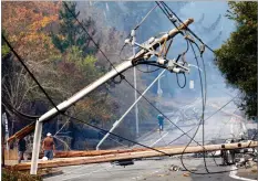  ?? AP PHOTO BY NHAT V. MEYER ?? In this Oct. 10 file photo, people walk past a fallen transforme­r and downed power lines on Parker Hill Road in Santa Rosa.