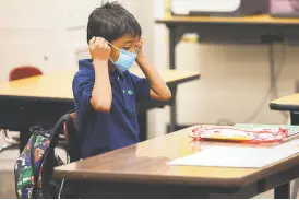  ?? Jessica Christian / The Chronicle ?? Top: Malchester Brown IV, 6, and his father, Malchester Brown III, arrive at Thornhill Elementary in Oakland. Above: Secondgrad­er Ernesto Beltran Pastrana puts on his mask in his classroom at Garfield Elementary. Right: Principal Alicia Arenas (right) speaks with the mother of firstgrade­r Samantha Mejia as she arrives for the first day of partial inperson instructio­n at Garfield Elementary.