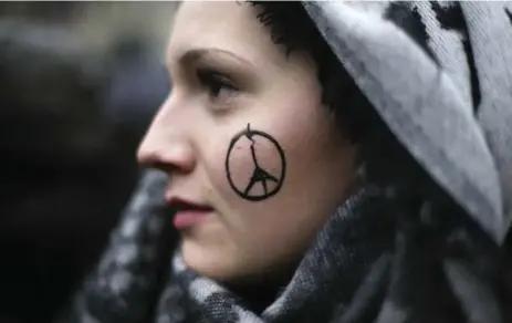  ?? MARKUS SCHREIBER/THE ASSOCIATED PRESS ?? A woman with the “Peace for Paris” symbol on her face in Paris. Artist Jean Jullien “felt compelled to reach out to show support” by drawing the emblem.