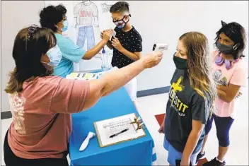  ?? LM OTERO AP ?? Amid concerns of the spread of the coronaviru­s, teachers check student temperatur­es before a summer STEM camp in Texas in July.