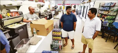  ?? Christian Abraham / Hearst Connecticu­t Media ?? Sam Chidella, at right, stops by Mama Carmela's Deli in Darien, on July 26. In center is Sam's son Phaneendra. Chidella, a manager at Darien Exxon Mobil for 25 years, is retiring and heading back to India, his home country.