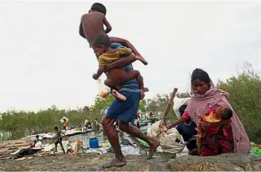  ??  ?? Desperate measures: Rohingya refugees tending to their children in Bangladesh after crossing the Naf River with an improvised raft to reach the country. — Reuters