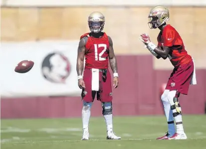  ?? JOE RONDONE/ASSOCIATED PRESS ?? FSU sophomore QB James Blackman takes a snap as junior QB Deondre Francois (12) looks on during practice Monday in Tallahasse­e.