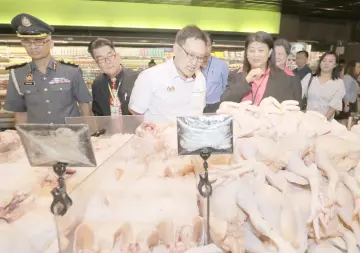  ??  ?? Chong (centre) inspects fresh chicken on sale at Everrise BDC, accompanie­d by Nawawi (left), Liew (Chong’s left) and others. — Photos by Chimon Upon