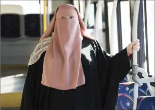  ?? GRAHAM HUGHES, THE CANADIAN PRESS ?? Warda Naili stands on a city bus in Montreal. The Quebec woman, a convert to Islam, said she decided to cover her face out of a desire to practise her faith more authentica­lly and to protect her modesty.