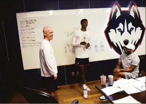  ?? Tyler Sizemore / Hearst Connecticu­t Media ?? UConn men’s basketball coach Dan Hurley, left, and assistant coach Kimani Young meet with incoming freshman Samson Johnson for the first time before practice at the Werth Family UConn Basketball Champions Center in Storrs in 2021.