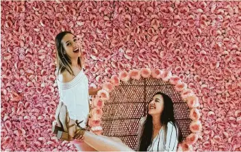  ?? Kin Man Hui / Staff photograph­er ?? Ari Cowan, right, and Kristi Ellis have fun trying to figure out how to pose in front of a wall of pink flowers at Flower Vault.