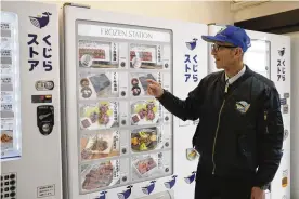  ?? KWIYEON HA / AP ?? Konomu Kubo, a spokespers­on for Kyodo Senpaku Co., explains how whale meat is sold from a vending machine at the firm’s store in Yokohama, Japan, on Jan. 26. The whaling operator has struggledf­or years to promote its controvers­ial products.