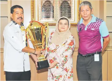  ??  ?? Jumaani receives the tournament trophy from organising chairman Ibrahim Abdul Rahman as PBBBNS deputy president Shaiful Bahri Shukri looks on.