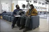  ?? TERESA CRAWFORD — THE ASSOCIATED PRESS ?? Herman Simmons, left, makes a vaccinatio­n appointmen­t for Theopulis Polk, right, at a Chicago laundromat on Saturday. Simmons is a community outreach worker enlisted by Saint Anthony Hospital.