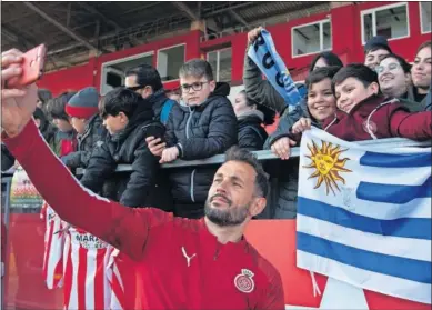  ??  ?? El delantero Stuani se hace un selfie con varios aficionado­s del Girona.