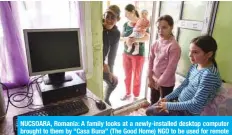  ??  ?? NUCSOARA, Romania: A family looks at a newly-installed desktop computer brought to them by “Casa Buna” (The Good Home) NGO to be used for remote schooling in this village on May 12, 2020. — AFP