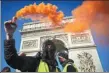  ?? GETTY IMAGES ?? A ‘yellow vest’ protestor holds a yellow flare aloft during protests in Paris on Saturday.