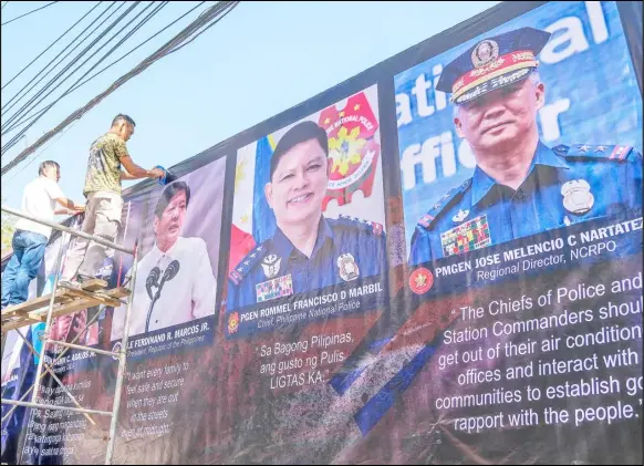  ?? PHOTOGRAPH BY KING RODRIGUEZ FOR THE DAILY TRIBUNE ?? WORKERS put up on Tuesday a huge tarpaulin bearing the likeness of President Ferdinand Marcos Jr., newly-appointed Philippine National Police chief Police General Rommel Francisco Marbil and National Capital Region Police Office regional director PMGen Jose Melencio Nartatez Jr., outside the Manila Police District headquarte­rs in Ermita, Manila.