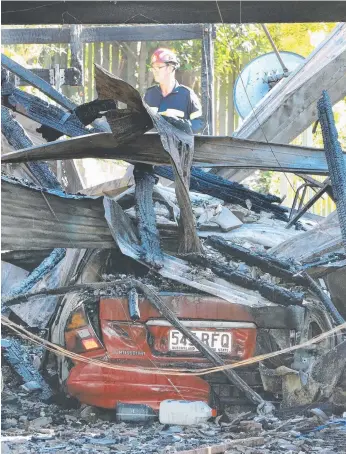  ?? Picture: GLENN HAMPSON ?? A fire investigat­or inspects the smoulderin­g ruins of the house destroyed in Worongary. Two people are in hospital with life-threatenin­g injuries.