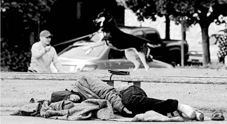  ?? TED S. WARREN/AP ?? A man sleeps in May at a Seattle park. Only some 400 homeless people in Washington state’s biggest city have been diagnosed with the coronaviru­s.