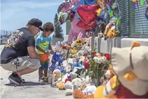  ?? ALLEN J. SCHABEN/LOS ANGELES TIMES VIA TNS ?? Albert Lamonte helps his son, Marcel Lamonte, 2, place flowers and a pinwheel at a makeshift memorial to remember 6-year-old Aiden Leos, who was shot and killed during a road rage incident in Orange, Calif., in May.