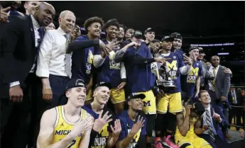  ??  ?? Michigan players and coaches celebrate after a 58-54 win over Florida State in an NCAA men’s college basketball tournament regional final Saturday in Los Angeles. AP PHOTO/ALEX GALLARDO