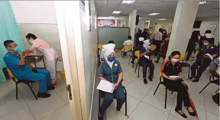  ?? BERNAMA PIC ?? A frontliner (left) receives the Covid-19 vaccine jab as others wait their turn at the Lam Wah Ee Hospital vaccinatio­n centre in George Town on Monday.