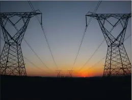  ??  ?? Eskom power lines run through an open field as the sun rises.