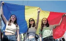  ?? | AFP ?? WOMEN hold a Moldovan flag during a rally to support the European path of the country, in Chisinau, Moldova, yesterday.