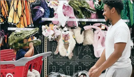  ?? AP PHOTO/BRYNN ANDERSON ?? Liam Vasquez, 2, left, and his father, Will Vasquez, right, try on Halloween masks at a Target store on Oct. 3 in Pembroke Pines, Fla. Discounter­s like Walmart and Target are expanding their costume offerings and creating designated sections where customers can find more of their Halloween needs in one place.