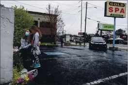  ?? BEN GRAY — AP PHOTO ?? Mallory Rahman and her daughter Zara Rahman, 4, who live nearby, pause after bringing flowers to the Gold Spa massage parlor in Atlanta, the day after eight people were killed at three massage spas in the Atlanta area.