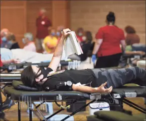  ?? Tyler Sizemore / Hearst Connecticu­t Media ?? Greenwich resident Mary Figgie reads a book while donating blood at the American Red Cross blood drive at Temple Sholom in Greenwich on Aug. 2.