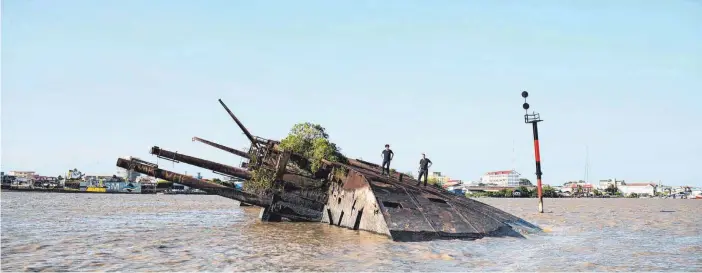  ?? FOTOS: DPA ?? Zwei Touristen stehen auf dem Wrack der „Goslar“. Das deutsche Frachtschi­ff war am 10. Mai 1940 vor Paramaribo, der Hauptstadt Surinams, versenkt worden.