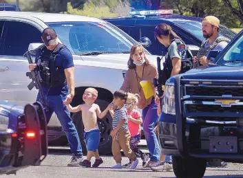  ?? ADOLPHE PIERRE-LOUIS/JOURNAL ?? Officers escort children from Christ Lutheran School after gunfire erupted in the parking lot Thursday in Northeast Albuquerqu­e. One father told his 3-year-old daughter, “Hold on baby girl,” after they heard gunshots.