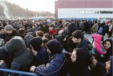  ?? Maxim Guchek / BelTA ?? Migrants line up for food aid at a logistics center near Grodno, Belarus, along the border with Poland. The European Union has accused the nation of encouragin­g the flow of migrants.