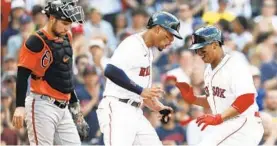  ?? MICHAEL DWYER | AP ?? The Red Sox’s Rafael Devers, right, celebrates his three-run homer with Xander Bogaerts in front of Orioles catcher Austin Wynns during the first inning Saturday in Boston. The Red Sox handed the Orioles their worst loss of the season.