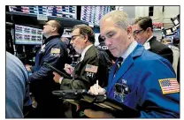  ?? AP/RICHARD DREW ?? Timothy Nick (right) works with fellow traders on the floor of the New York Stock Exchange on Wednesday. Stocks opened sharply lower on Wall Street, but the markets recovered later in the day as fears of an escalating trade dispute between the U.S. and...