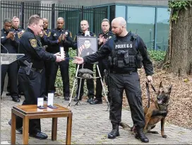  ?? EMILY HANEY PHOTOS / EMILY.HANEY@AJC.COM ?? Police Chief James Conroy presents Indi’s trainer, officer Norman Larsen, with an Exceptiona­l Merit award Wednesday.