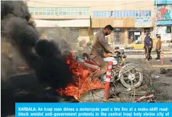  ??  ?? KARBALA: An Iraqi man drives a motorcycle past a tire fire at a make-shift roadblock amidst anti-government protests in the central Iraqi holy shrine city of Karbala yesterday. —AFP