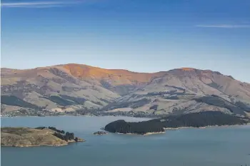  ?? JOHN KIRK-ANDERSON/THE PRESS ?? The sunlit summit of Mt Herbert/Te Ahu Pātiki, left, alongside Mt Bradley, providing the timeless backdrop to Charteris Bay and Lyttelton Harbour.