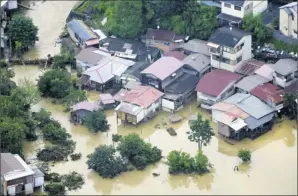 ?? Kyodo News photos via AP ?? Flash flooding: A neighborho­od in Kyoto, Japan’s old capital, is submerged Sunday after heavy rainfall of up to 3.5 inches per hour flooded about 100 houses each in the cities of Kameoka and Kyoto.